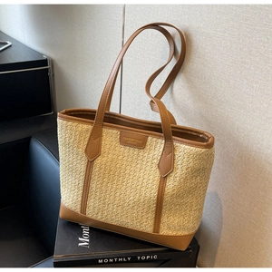 Close-up of beige woven tote bag with brown leather trim and fashion brand label