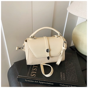 Détail du sac beige en cuir PU et paille avec fermoir tournant doré sur un livre