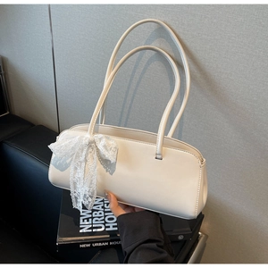 Detail of a creamy white PU leather baguette bag with a white lace bow and dual straps