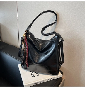 Dettaglio della borsa hobo in pelle lucida nera con chiave dorata e nappa pendente