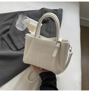 Close-up of white quilted leather bucket bag with silver metal hardware and top handle