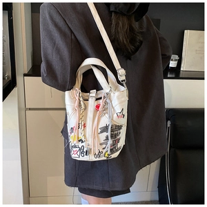 Detail of white canvas bucket bag with colorful graffiti and woven rope accessories