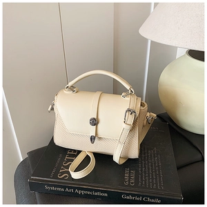 Détails du sac crème en cuir et texture tissée avec fermoir argenté sur un livre