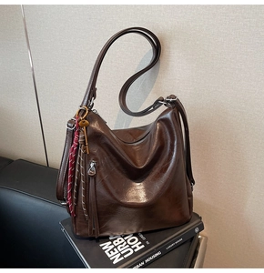 Dettaglio zaino in pelle cerata marrone scuro con chiavi in metallo e nappa intrecciata
