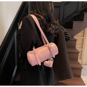 Pink cilinder oil wax leather shoulder bag with heart charm shown on a black suit