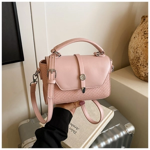 Détails du sac rose montrant les coutures en cuir et le matériau tissé avec boucle argentée