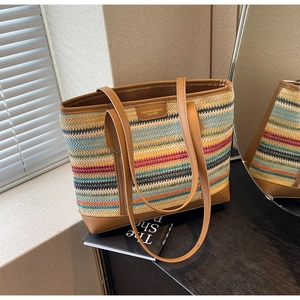 Close-up of a colorful woven straw tote bag with brown leather accents and a fashion label