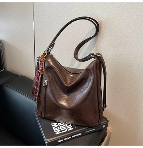 Dettaglio della pelle cerata vintage e finiture in ottone su una borsa a tracolla marrone
