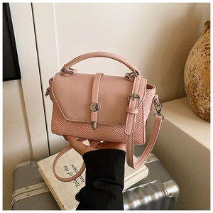 Détail du sac à bandoulière rose avec cuir lisse, texture tissée et fermoir rotatif en métal