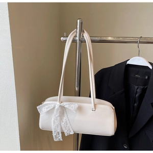 Detail of white rectangle pillow bag with lace bow decoration and slim shoulder straps
