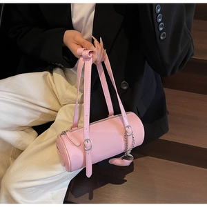 Pink cylinder barrel bag with silver hardware and heart pendant held by model