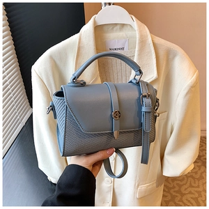 Détail du sac à main bleu clair en cuir et tissu tissé avec boucle métallique magnétique
