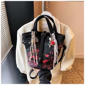 Detail of black denim tote bag with red graffiti heart prints and colorful charms