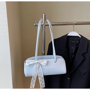 Detail of light blue rectangle handbag with large white lace bow on silver display stand