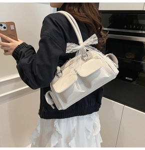 Close-up of cream Boston bag with lace bow detail and functional front pockets