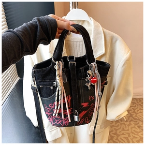 Detail of denim bucket bag with pink graffiti patterns and balloon dog charm