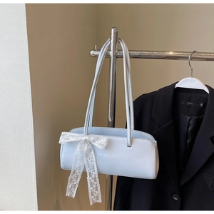 Detail of light blue leather baguette bag featuring a large white lace bow decoration
