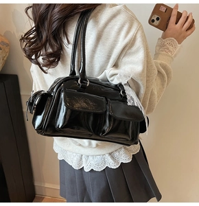 Detail of black patent leather Boston bag featuring lace ribbon and functional pockets