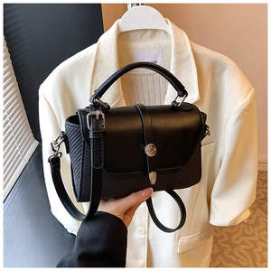 Détail du sac bandoulière noir avec texture tissée, poignée en cuir et boucle argent