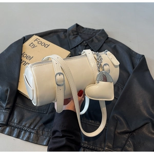 Close-up of white cylinder handbag with heart charm detail over black jacket