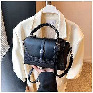 Détail du sac bandoulière noir avec rabat lisse et motif tissé sur la partie basse
