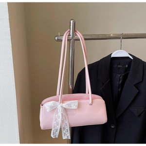Detail of pink patent leather pillow bag featuring a decorative white lace bow