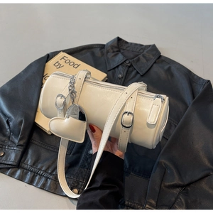 Detail of minimalist cream oil wax leather cylinder bag with heart charm and silver zipper