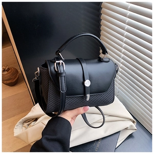 Détail du sac bandoulière noir avec textures mixtes et accents de clous métalliques