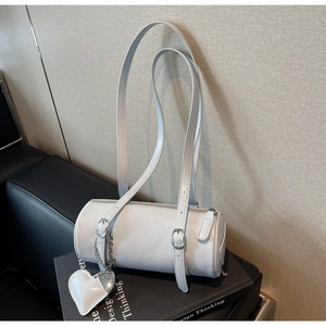 Detail view of white cylinder shoulder bag in oil wax leather with heart pendant
