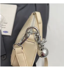 Vue détaillée de la ferronnerie argentée et du pendentif sphérique du sac crème