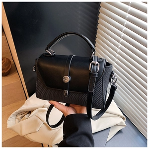 Détail de la texture en cuir noir avec motif tressé et fermoir métallique argenté