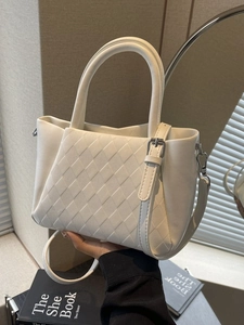Chic beige quilted bucket bag with dual handles and detachable shoulder strap in a minimalist setting