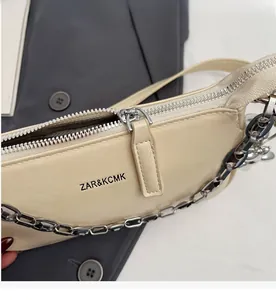 Détail de la chaîne argentée et de la fermeture éclair sur sac bandoulière en cuir blanc
