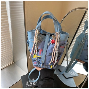 Detail of light blue denim bucket bag with graffiti prints and colorful charms