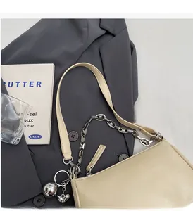 Détail du sac bandoulière blanc cassé avec chaîne argentée, pendentif cœur et logo