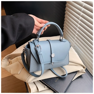 Détail du sac bandoulière bleu clair avec texture tissée et boucle en métal rond