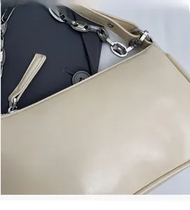 Gros plan du sac sous l'aisselle en cuir blanc cassé avec chaîne argentée et logo