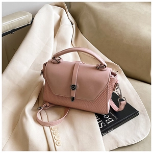 Détail du sac à bandoulière rose clair avec patchwork cuir et tissé sur un blazer crème