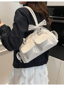Cream white Boston shoulder bag with lace bow accents shown on a model's arm