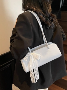 Light blue faux leather baguette bag with lace bow accessory shown on shoulder