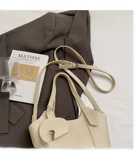 Detail of lychee textured leather bucket bag with adjustable strap and designer pendant