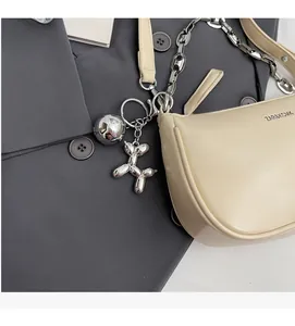 Détail du sac crème avec bandoulière chaîne argentée et charm chien ballon sur costume