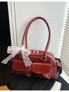 Dark red patent Boston bag with double pockets and white lace bows in a lifestyle setting