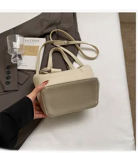Detail of beige lychee pattern leather bucket bag with adjustable strap in a lifestyle setting