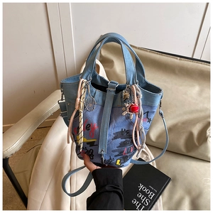 Detail of a patchwork denim tote bag featuring colorful graffiti and vibrant charms