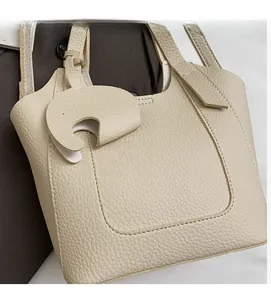 Detail of cream lychee pattern leather bucket bag with fine stitching and charm