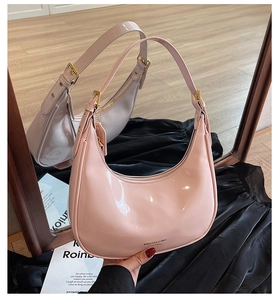 Pink patent leather half-moon bag with golden zipper and logo detail in mirror view