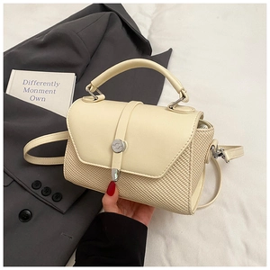 Détail du sac à bandoulière blanc crème avec texture tissée et boucle ronde métallique