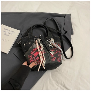 Detail of black denim bucket bag with red graffiti and various decorative charms
