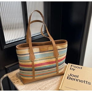 Detail of colorful woven straw tote bag featuring leather handles and reinforced base corners